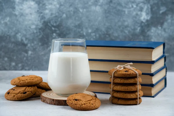 Glass of milk, sweet cookies and book on marble table — Stock Photo, Image