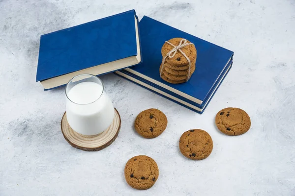 Glass of milk, chocolate chip cookies and book on marble surface — Stock Photo, Image