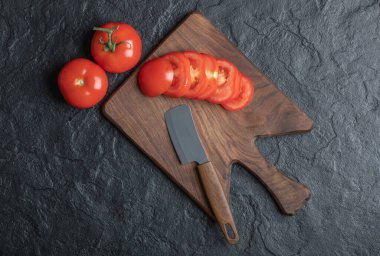 Bir grup domates, dilimlenmiş ya da siyah arka planda.