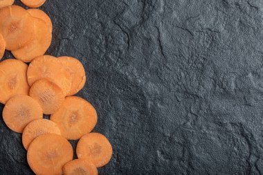 Taze soyulmuş havuç dilimleri. Siyah arkaplanda