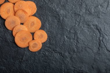 Siyah zemin üzerinde taze organik dilimlenmiş havuç.