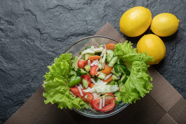 건강에 좋은 야채 샐러드의 사진을 닫고 배경이 검은 레몬과 함께 있는 모습 — 스톡 사진