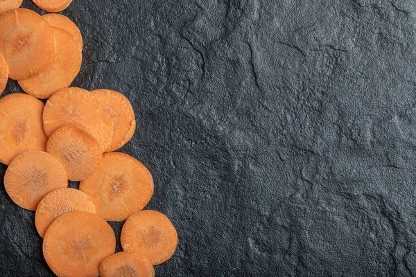 Taze soyulmuş havuç dilimleri. Siyah arkaplanda