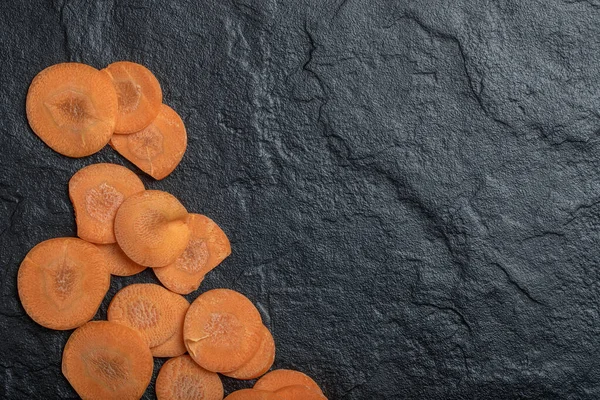 Taze soyulmuş havuç dilimleri. Siyah arkaplanda