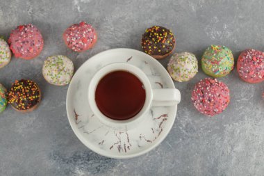 Bir fincan çay ve renkli tatlı çörekler.