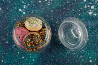 Küçük renkli çöreklerle dolu cam bir kavanoz.