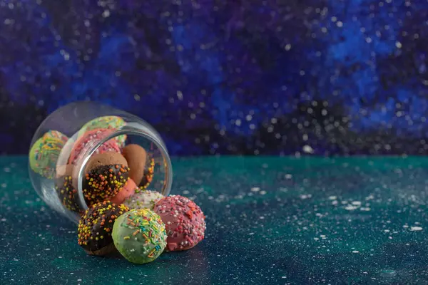 Стакан, полный маленьких красочных пончиков — стоковое фото