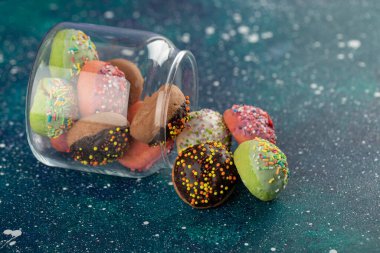 Küçük renkli çöreklerle dolu cam bir kavanoz.