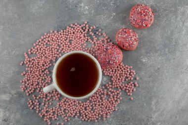 Pembe tatlı çörekler ve bir fincan çay.