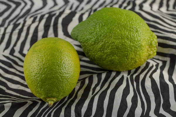 Limones verdes sobre un hermoso mantel —  Fotos de Stock
