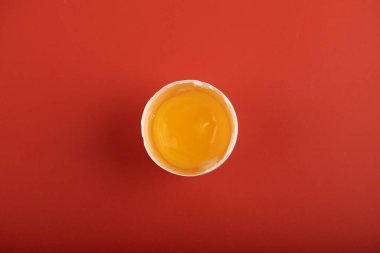 Kırmızı arka planda kırılmış organik yumurta.