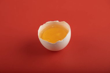 Kırmızı arka planda kırılmış organik yumurta.