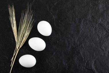 Siyah arka planda iki beyaz yumurta ve kulak.