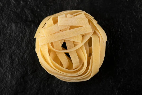 Raw tagliatelle nests on black background — Stock Photo, Image