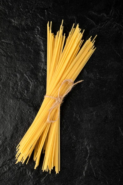 Spaghetti crudi legati con corda su fondo nero — Foto Stock