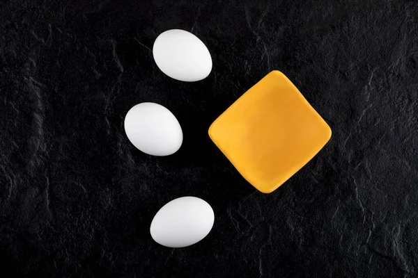 Huevos blancos crudos y tazón pequeño sobre fondo negro — Foto de Stock