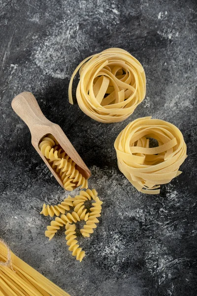 大理石背景上的Tagliatelle巢和fusilli — 图库照片