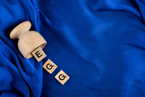 Lettres en bois orthographiées oeuf sur tissu bleu — Photo