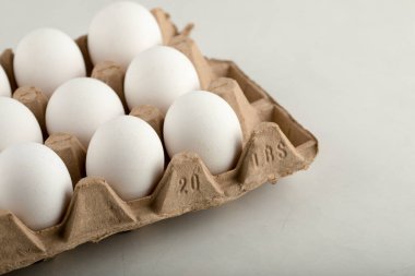 Beyaz arka planda yumurta kutusunda çiğ tavuk yumurtası.