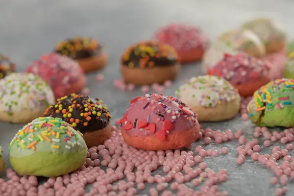 Kleurrijke kleine donuts met hagelslag en een kopje thee — Stockfoto