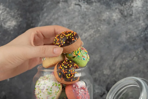 Mujer mano sosteniendo una pequeña rosquilla de chocolate — Foto de Stock