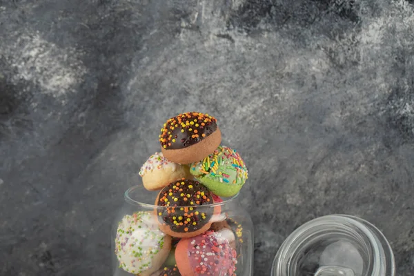 Un frasco de vidrio lleno de pequeñas rosquillas de colores —  Fotos de Stock