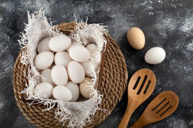 Beyaz çiğ tavuk yumurtası dolu ahşap bir sepet.