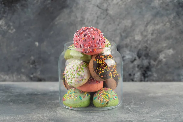 Een glazen pot vol kleine kleurrijke donuts — Stockfoto