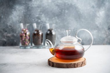 Tahta üzerinde çay olan camdan bir çaydanlık.