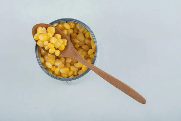 A wooden spoon full of popcorn seeds on a white background — Stock Photo, Image