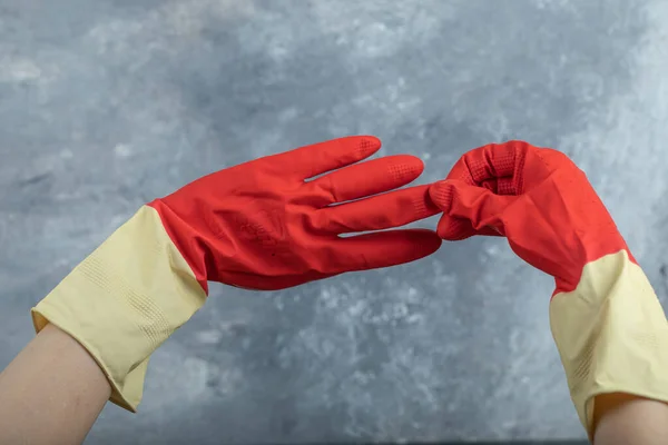 Hands wearing red protective gloves on marble background — Stock Photo, Image