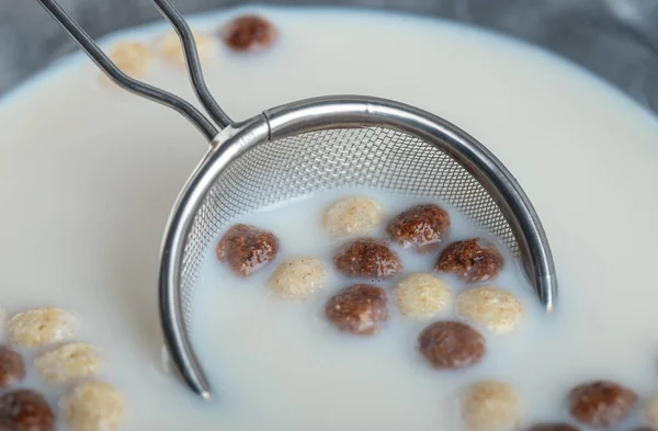 Bolas de cereales dulces y tazón de leche sobre fondo de mármol —  Fotos de Stock
