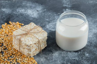 Bir yığın çıtır ekmek ve mermer zemin üzerinde bir bardak süt.