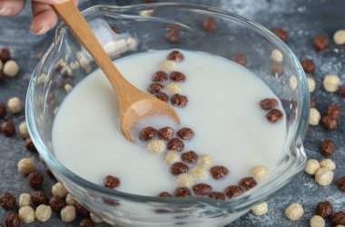 Kadın eli kaşık dolusu mısır gevreği toplarını tutuyor.