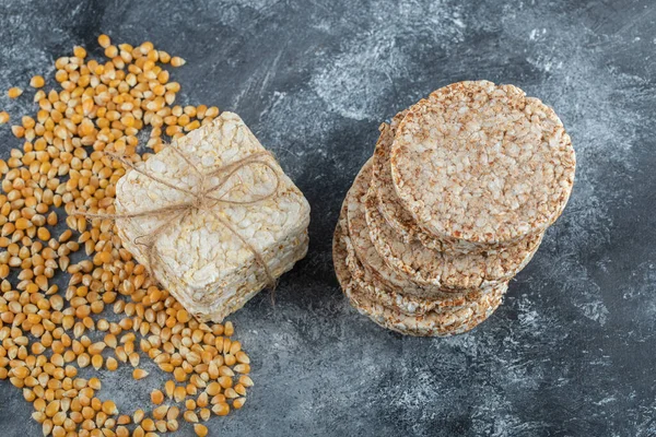 Dos tipos de pan crujiente y semillas de maíz crudo sobre fondo de mármol —  Fotos de Stock