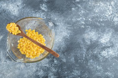 Tahta kaşıkla cam kasede bir yığın mısır.