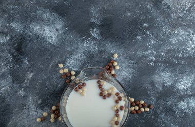 Tatlı gevrek topları ve mermer arka planda bir kase süt.