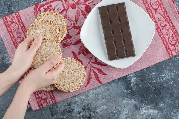 Mãos de mulher segurando pão de arroz crocante com barra de chocolate — Fotografia de Stock