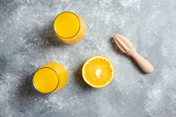 Vasos de zumo de naranja y un escarificador de madera — Foto de Stock
