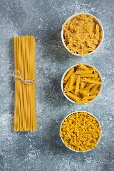 Olika typer av pasta på en grå bakgrund — Stockfoto
