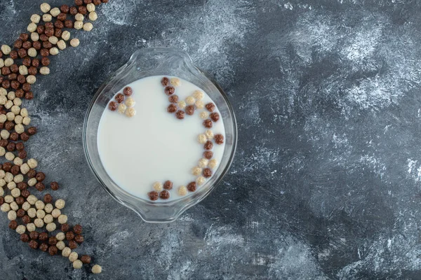 Bolas de cereales dulces y tazón de leche sobre fondo de mármol —  Fotos de Stock