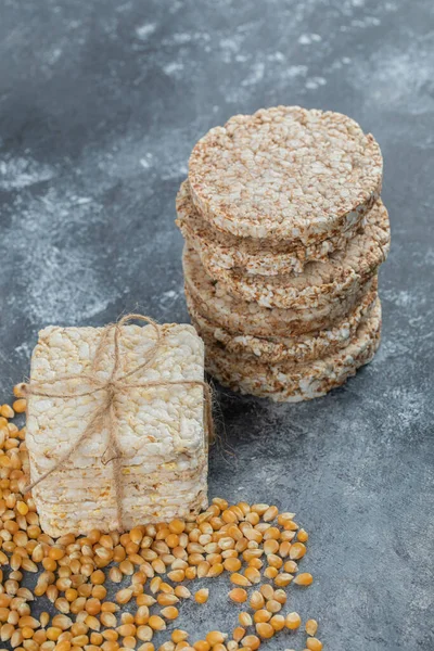 Two types of crispbread and raw corn seeds on marble background