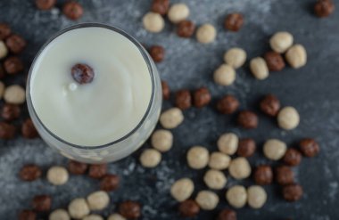 Süt bardağına saçılmış mısır gevreği topları.