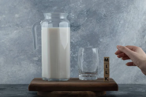 Жіноча рука намагається тримати дерев'яні літери зі свіжим молоком — стокове фото