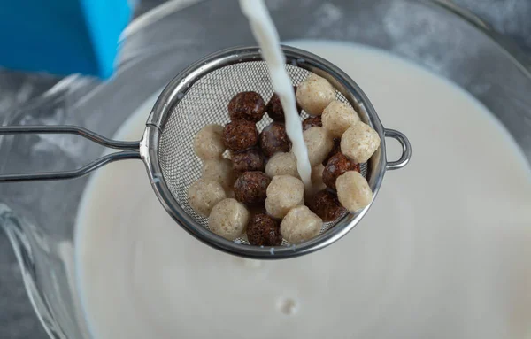 Cuchara coladora llena de bolas de cereal encima de la leche —  Fotos de Stock