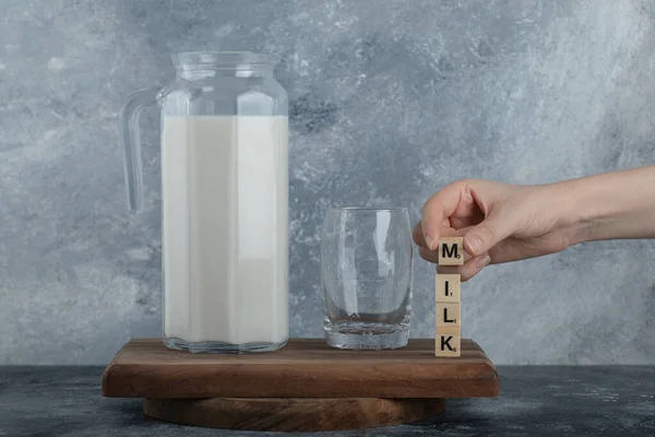 Női kezek fa betűkkel és friss tejjel — Stock Fotó