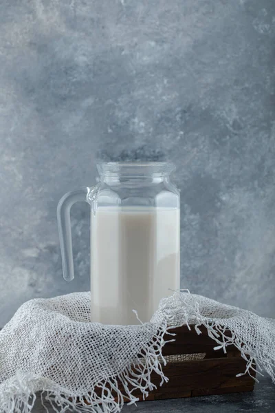 Jarro de vidro de leite em caixa de madeira com serapilheira — Fotografia de Stock