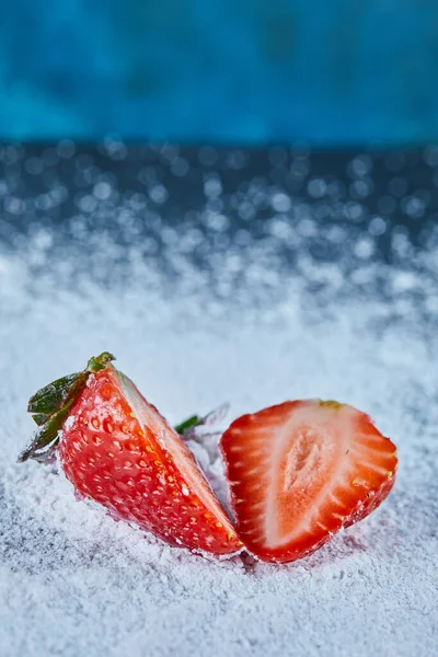 Frische Erdbeerscheiben auf blauem Hintergrund mit Puder — Stockfoto
