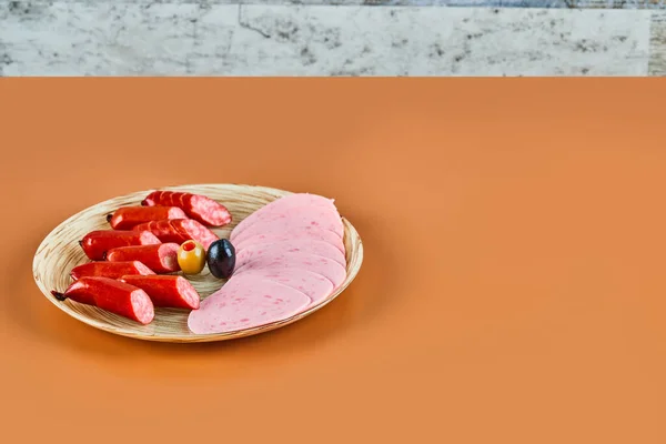 Нарезанные сосиски на тарелке и на оранжевом фоне — стоковое фото