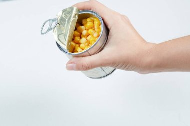 Beyaz arka planda bir kutu haşlanmış mısır tutarken